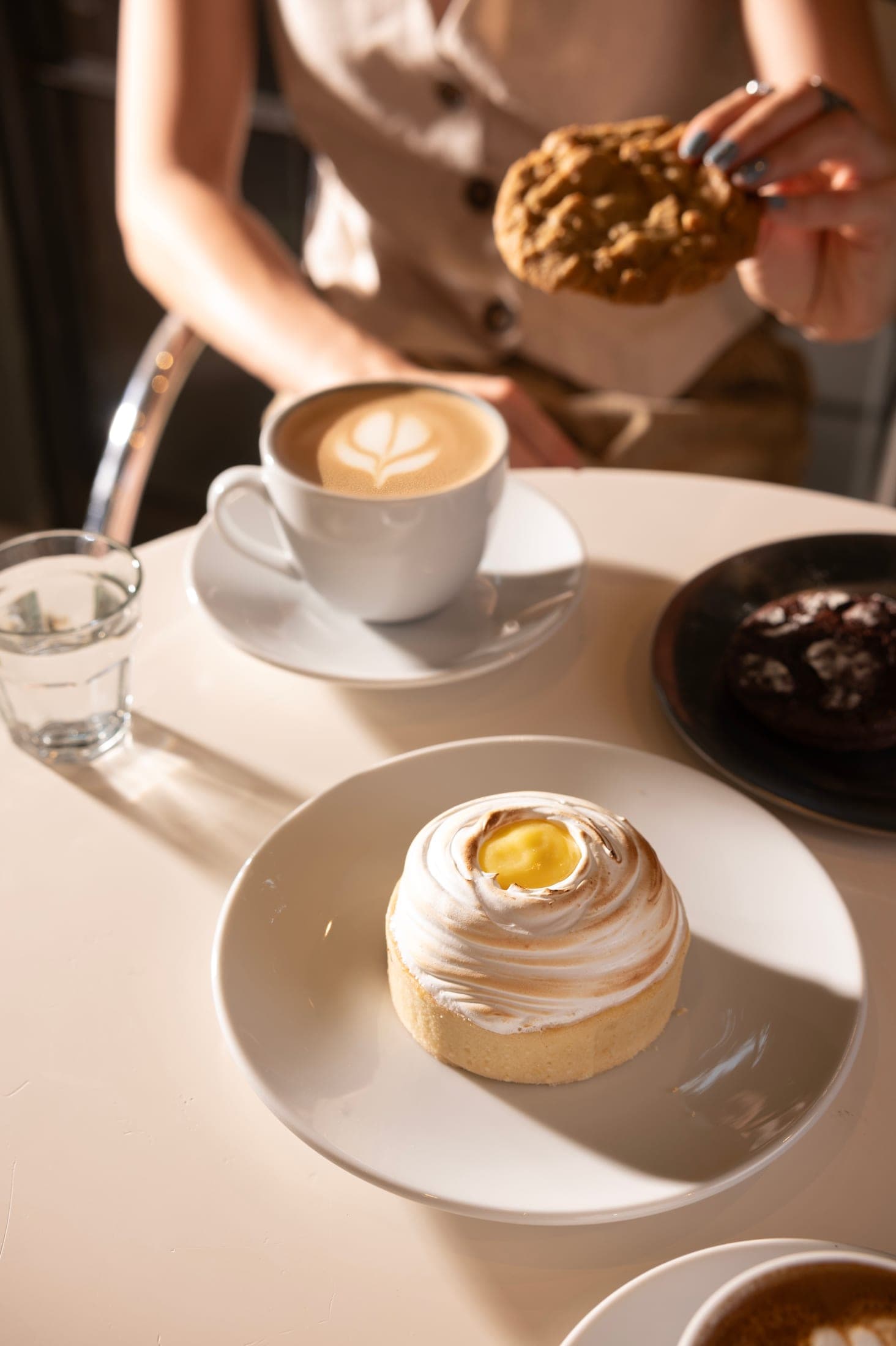 Café con arte latte junto a una tarta de limón merengada, sobre la mesa